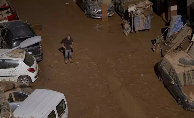 A man stands next to houses affected by floods in Valencia, Spain, Thursday, Oct. 31, 2024. (AP Photo/Alberto Saiz)