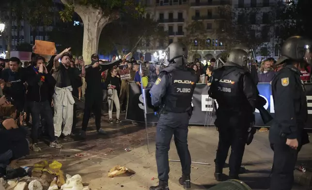 Demonstrators shout as riot police watches duringa protest organized by social and civic groups, denouncing the handling of recent flooding under the slogan "Mazón, Resign," aimed at the president of the regional government Carlos Mazon, in Valencia, Spain, Saturday, Nov. 9, 2024. (AP Photo/Emilio Morenatti)