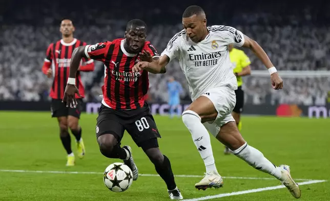 Real Madrid's Kylian Mbappe, right, and AC Milan's Yunus Musah battle for the ball during the Champions League opening phase soccer match at the Santiago Bernabeu stadium in Madrid, Spain, Tuesday, Nov. 5, 2024. (AP Photo/Manu Fernandez)