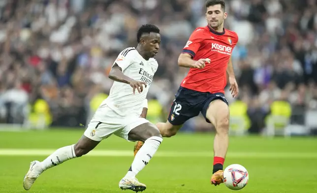 Real Madrid's Vinicius Junior challenges for the ball with Osasuna's Jesus Areso during the Spanish La Liga soccer match between Real Madrid and Osasuna at the Santiago Bernabeu stadium in Madrid, Spain, Saturday, Nov. 9, 2024. (AP Photo/Jose Breton)