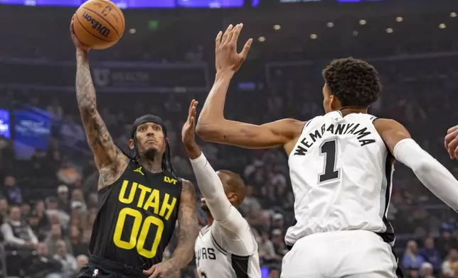 Utah Jazz guard Jordan Clarkson (00) takes the ball inside, as San Antonio Spurs guard Chris Paul (3) and San Antonio Spurs center Victor Wembanyama (1) defend during the first half of an NBA basketball game, Thursday, Oct. 31, 2024, in Salt Lake City. (AP Photo/Rick Egan)