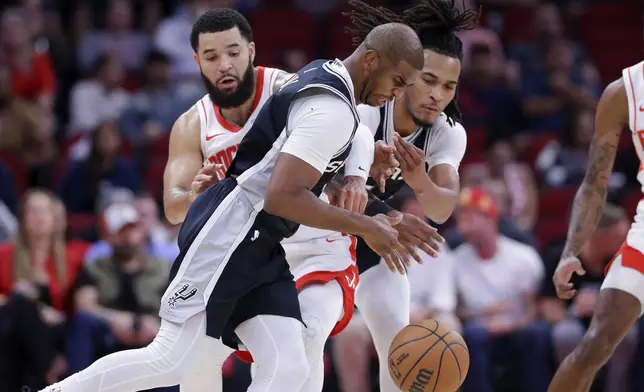 San Antonio Spurs guard Chris Paul, front, loses the ball as Houston Rockets guard Fred VanVleet, left, reaches in and Spurs guard Stephon Castle, right, tries to grab the ball during the first half of an NBA basketball game Wednesday, Nov. 6, 2024, in Houston. (AP Photo/Michael Wyke)