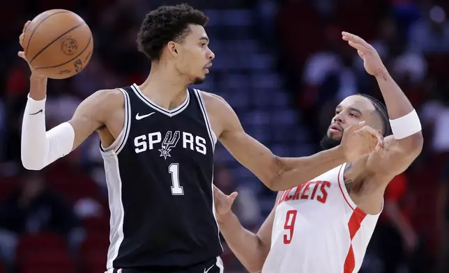 San Antonio Spurs center Victor Wembanyama (1) looks to pass the ball under pressure from Houston Rockets forward Dillon Brooks (9) during the first half of an NBA basketball game Wednesday, Nov. 6, 2024, in Houston. (AP Photo/Michael Wyke)