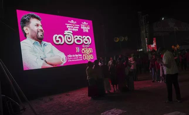 Supporters of National People's Power pose for selfie photos next to election propaganda carrying a portrait of president Anura Kumara Dissanayake after a public rally ahead of Thursday's parliamentary election Gampaha, Sri Lanka, Monday, Nov. 11, 2024. (AP Photo/Eranga Jayawardena)