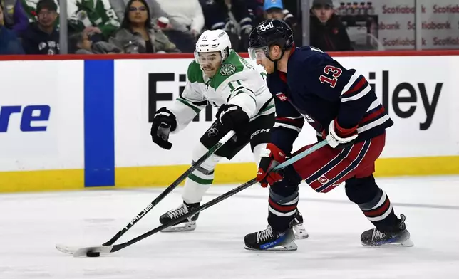 Dallas Stars' Logan Stankoven (11) and Winnipeg Jets' Gabriel Vilardi (13) reach for a loose puck during the second period of an NHL hockey game in Winnipeg, Manitoba, Saturday, Nov. 9, 2024. (Fred Greenslade/The Canadian Press via AP)