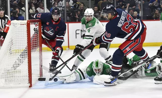 Dallas Stars' goaltender Casey DeSmith (1) makes a save on Winnipeg Jets' Nino Niederreiter (62) as Miro Heiskanen (4) defends against Adam Lowry (17) during the second period of an NHL hockey game in Winnipeg, Manitoba, Saturday, Nov. 9, 2024. (Fred Greenslade/The Canadian Press via AP)