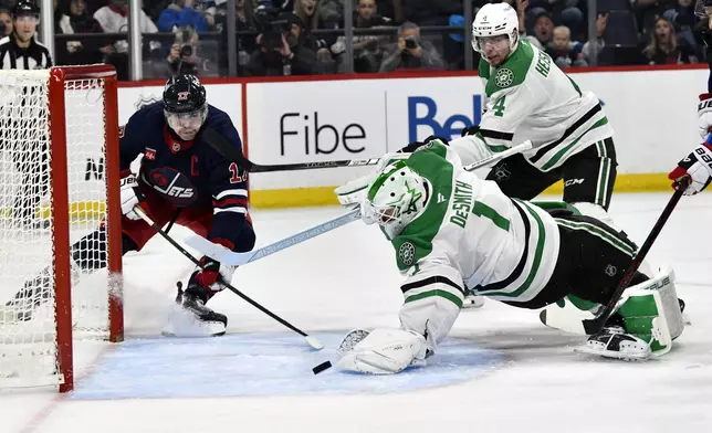 Dallas Stars goaltender Casey DeSmith (1) makes a save on Winnipeg Jets' Adam Lowry (17) during the second period of an NHL hockey game in Winnipeg, Manitoba, Saturday, Nov. 9, 2024. (Fred Greenslade/The Canadian Press via AP)