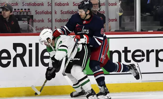 Dallas Stars' Colin Blackwell (15) is checked by Winnipeg Jets' Colin Miller (6) during the second period of an NHL hockey game in Winnipeg, Manitoba, Saturday, Nov. 9, 2024. (Fred Greenslade/The Canadian Press via AP)
