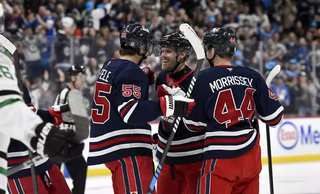 Winnipeg Jets' Nikolaj Ehlers (27) celebrates his goal against the Dallas Stars with Mark Scheifele (55) and Josh Morrissey (44) during the second period of an NHL hockey game in Winnipeg, Manitoba, Saturday, Nov. 9, 2024. (Fred Greenslade/The Canadian Press via AP)