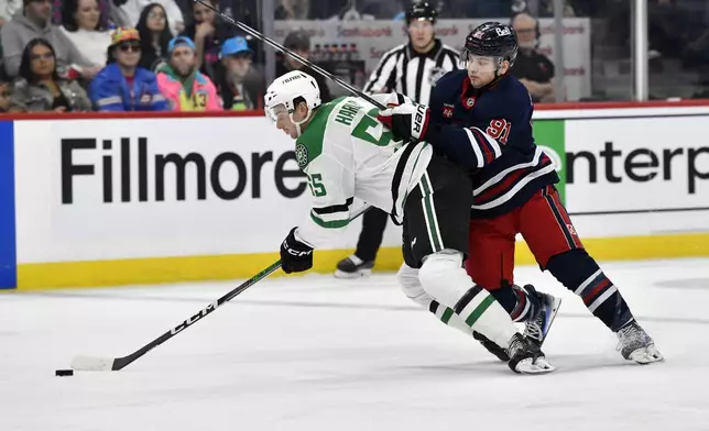 Winnipeg Jets' Cole Perfetti (91) checks Dallas Stars' Thomas Harley (55) during the second period of an NHL hockey game in Winnipeg, Manitoba, Saturday, Nov. 9, 2024. (Fred Greenslade/The Canadian Press via AP)