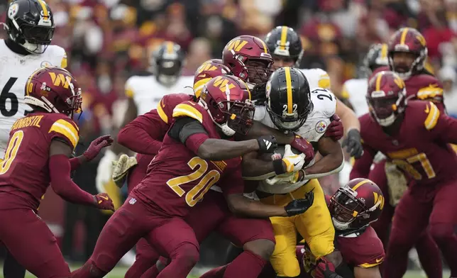 Pittsburgh Steelers running back Najee Harris (22) is stopped by Washington Commanders safety Quan Martin (20) and teamates during the second half of an NFL football game, Sunday, Nov. 10, 2024, in Landover, Md. (AP Photo/Stephanie Scarbrough)