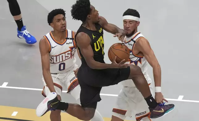 Utah Jazz guard Collin Sexton, center, drives to the basket as Phoenix Suns' Ryan Dunn (0) and Devin Booker, right, defend during the first half of an Emirates NBA Cup basketball game Tuesday, Nov. 12, 2024, in Salt Lake City. (AP Photo/Rick Bowmer)