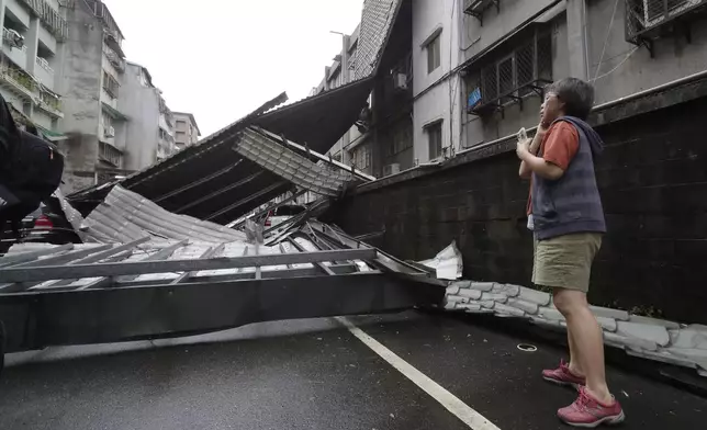 A woman looks at a row of blown roofs destroyed by the wind of Typhoon Kong-rey in Taipei, Taiwan, Friday, Nov. 1, 2024. (AP Photo/Chiang Ying-ying)
