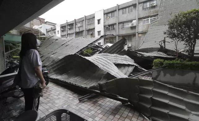 A woman looks at a row of blown roofs destroyed by the wind of Typhoon Kong-rey in Taipei, Taiwan, Friday, Nov. 1, 2024. (AP Photo/Chiang Ying-ying)
