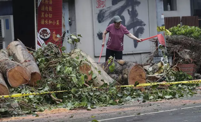 A woman clears debris in the aftermath of Typhoon Kong-rey in Taipei, Taiwan, Friday, Nov. 1, 2024. (AP Photo/Chiang Ying-ying)