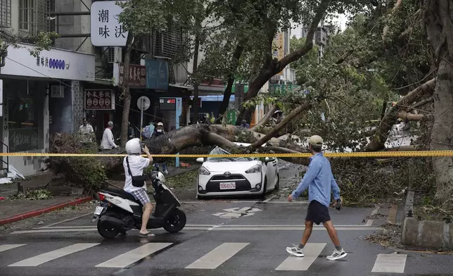 People walk past an area destroyed by the wind from Typhoon Kong-rey in Taipei, Taiwan, Friday, Nov. 1, 2024. (AP Photo/Chiang Ying-ying)