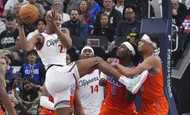 Los Angeles Clippers forward Kai Jones, left, passes the ball as Oklahoma City Thunder guard Luguentz Dort, second from right, and forward Ousmane Dieng, right, defend during the first half of an NBA basketball game, Saturday, Nov. 2, 2024, in Inglewood, Calif. (AP Photo/Mark J. Terrill)