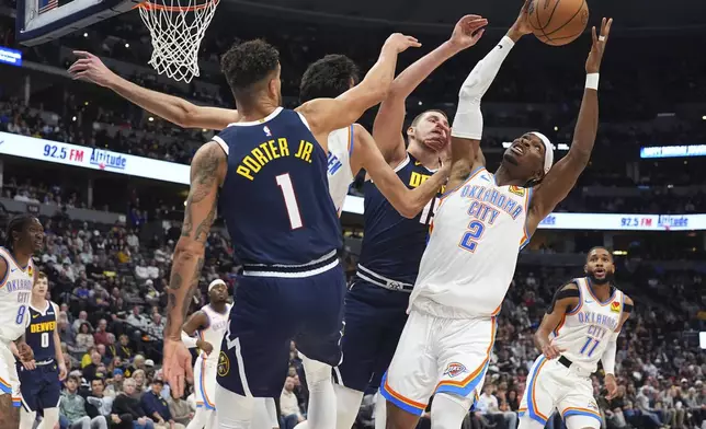 Oklahoma City Thunder guard Shai Gilgeous-Alexander, right, pulls in a rebound as forward Chet Holmgren, second from left, gets tangled up with Denver Nuggets forward Michael Porter Jr., far left, and center Nikola Jokic n the first half of an NBA basketball game Wednesday, Nov. 6, 2024, in Denver. (AP Photo/David Zalubowski)