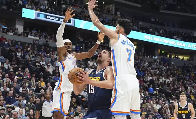 Denver Nuggets center Nikola Jokic, center, drives to the rim between Oklahoma City Thunder guard Shai Gilgeous-Alexander, left, and forward Chet Holmgren in the first half of an NBA basketball game Wednesday, Nov. 6, 2024, in Denver. (AP Photo/David Zalubowski)