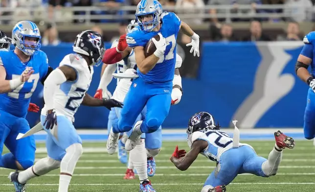 Detroit Lions tight end Sam LaPorta, center, runs the ball after a catch past Tennessee Titans cornerback Jarvis Brownlee Jr., right, during the second half of an NFL football game Sunday, Oct. 27, 2024, in Detroit. (AP Photo/Carlos Osorio)