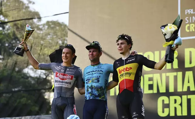 Mark Cavendish of Astana Qazaqstan, centre, Alpecin Deceunick's Jasper Philipsen, left, and Belgian Champion, Arnaud De Lie, of Lotto Destiny, right pose on the podium during the Prudential Singapore Tour De France Criterium, Sunday, November 10th, 2024. (AP Photo/Danial Hakim)