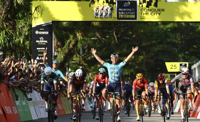 Mark Cavendish of Astana Qazaqstan, centre, celebrates after crossing the finish line during the Prudential Singapore Tour De France Criterium, Sunday, Nov. 10, 2024. (AP Photo/Danial Hakim)