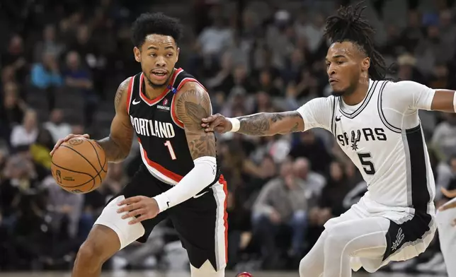 Portland Trail Blazers' Anfernee Simons (1) drives against San Antonio Spurs' Stephon Castle during the first half of an NBA basketball game, Thursday, Nov. 7, 2024, in San Antonio, Texas. (AP Photo/Darren Abate)