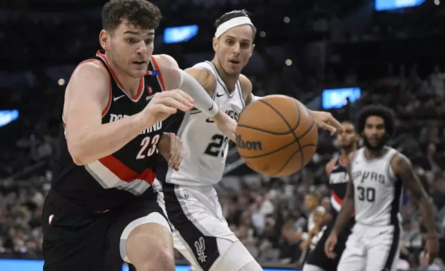 Portland Trail Blazers' Donovan Clingan, left, and San Antonio Spurs' Zach Collins chase the ball during the first half of an NBA basketball game, Thursday, Nov. 7, 2024, in San Antonio, Texas. (AP Photo/Darren Abate)