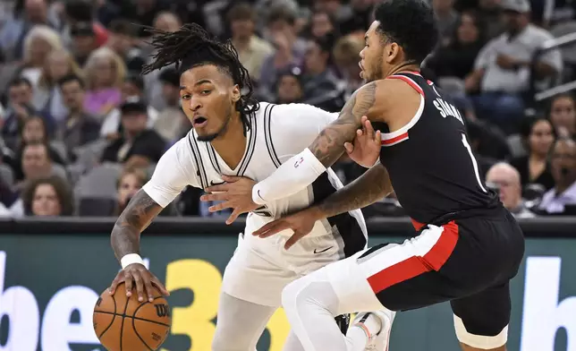 San Antonio Spurs' Stephon Castle, left, tangles with Portland Trail Blazers' Anfernee Simons during the second half of an NBA basketball game, Thursday, Nov. 7, 2024, in San Antonio. San Antonio won 118-105. (AP Photo/Darren Abate)