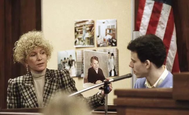 FILE - Erik Menendez listens to defense attorney Leslie Abramson while she holds a photograph of him as a young boy during testimony in Los Angeles, Sept. 29, 1993. (AP Photo/Nick Ut, File)