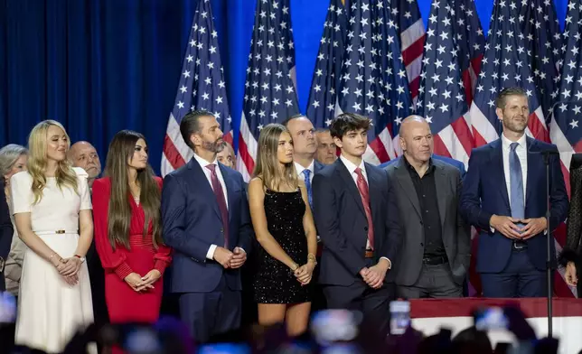 From left, Susie Wiles, Tiffany Trump, Tony Fabrizio, Kimberly Guilfoyle, Donald Trump Jr., Walt Nauta (hidden two people), Kai Madison Trump, Dan Scavino, Corey Lewandowski, Donald Trump III, Dana White, Chris LaCivita and Eric Trump, listen as Republican presidential nominee former President Donald Trump speaks at an election night watch party Wednesday, Nov. 6, 2024, in West Palm Beach, Fla. (AP Photo/Alex Brandon)