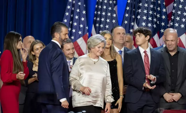 From left, Kimberly Guilfoyle, Tony Fabriozio, Donald Trump Jr., fourth from left, Justin Caporale, Susie Wiles, Kai Madison Trump, Dan Scavino, Corey Lewandowski, Donald Trump III and Dana White listen as Republican presidential nominee former President Donald Trump speaks at an election night watch party Wednesday, Nov. 6, 2024, in West Palm Beach, Fla. (AP Photo/Alex Brandon)