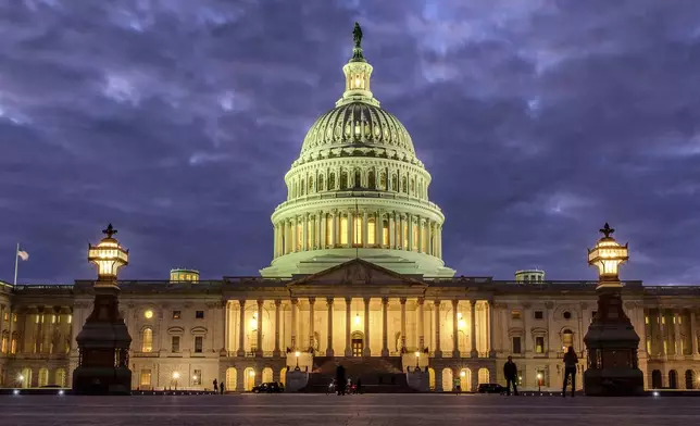 FILE - Lights shine inside the U.S. Capitol Building as night falls on Jan. 21, 2018, in Washington. (AP Photo/J. David Ake, File)