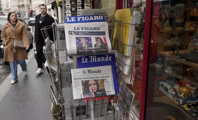 People walk past a newsstand with newspapers headlining on the US election, Tuesday, Nov. 5, 2024 in Paris. (AP Photo/Michel Euler)