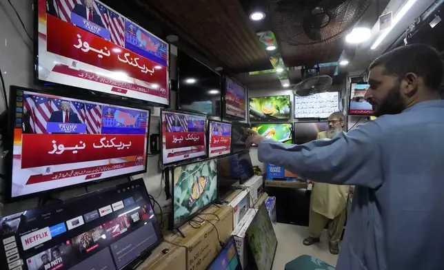 Pakistanis watch news channels broadcasting results of U.S. presidential elections, at a shop in Karachi, Pakistan, Wednesday, Nov. 6, 2024. (AP Photo/Fareed Khan)