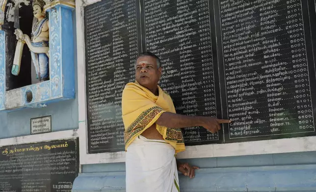 M. Natarajan, head priest of Sri Dharmasastha Hindu temple points out the name of Democratic presidential nominee Vice President Kamala Harris on a plaque, displaying names of donors written in Tamil language who donated for the renovation of temple, in Thulasendrapuram, the ancestral village of Harris, in Tamil Nadu state, India, Monday, Nov. 4, 2024. (AP Photo/Aijaz Rahi)