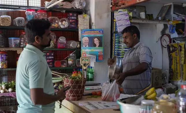 Manikandan Ganesan, right, a local shopkeeper, packs vegetables for a customer at his grocery store outside Sri Dharmasastha Hindu temple in Thulasendrapuram, the ancestral village of Democratic presidential nominee Vice President Kamala Harris, in Tamil Nadu state, India, Monday, Nov. 4, 2024. (AP Photo/Aijaz Rahi)