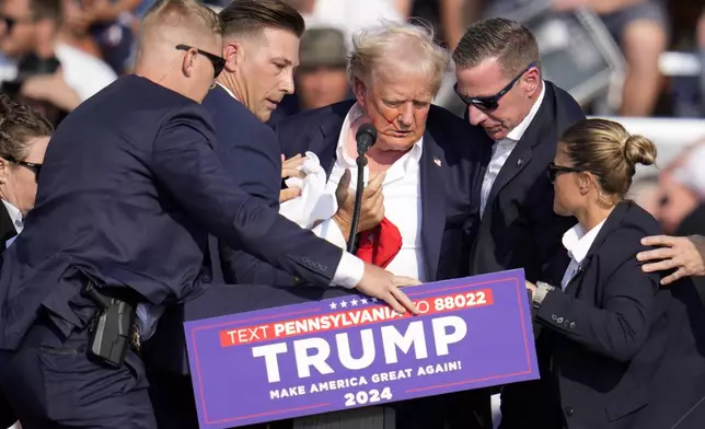 Republican presidential candidate former President Donald Trump is helped off the stage at a campaign event in Butler, Pa., on Saturday, July 13, 2024. (AP Photo/Gene J. Puskar)