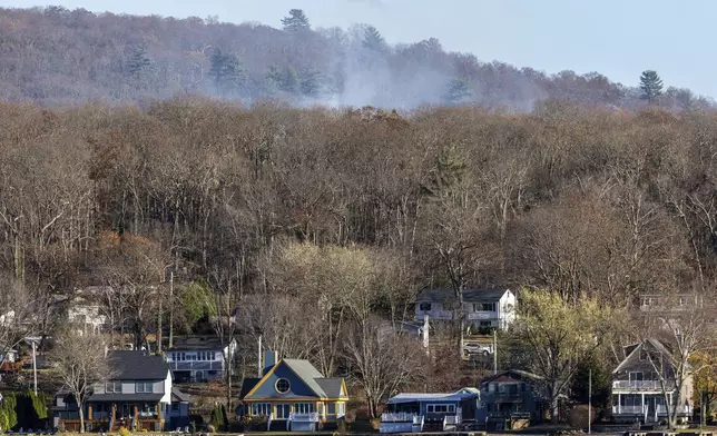 Smoke rises from a wildfire behind a row of lakefront properties in the town of Awosting, as seen from across Greenwood Lake, Lakeside, N.J., Monday, Nov. 11, 2024. (AP Photo/Stefan Jeremiah)