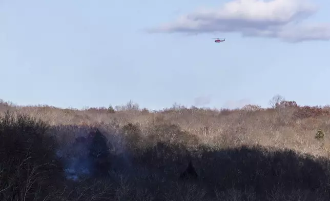 A New Jersey Forest Fire Service helicopter flies over a patch of wildfire near the town of Awosting, N.J., Monday, Nov. 11, 2024. (AP Photo/Stefan Jeremiah)