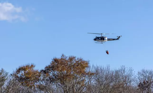 A New York State Police helicopter flies over the town of Awosting as seen from across Greenwood Lake, in Lakeside, N.J., Monday, Nov. 11, 2024. (AP Photo/Stefan Jeremiah)