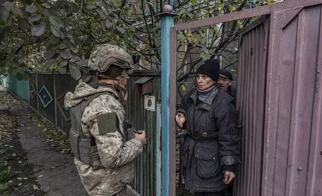 Pipa Vasyl, a policeman of the "White Angels", tries to convince a local woman to evacuate from Kurakhove, Donetsk region, Ukraine, on Nov. 7, 2024. (AP Photo/Anton Shtuka)