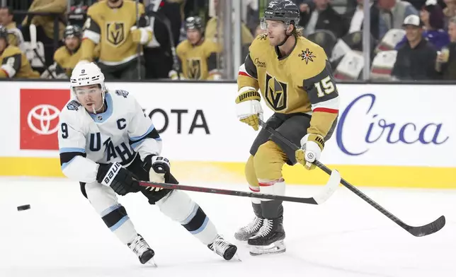 Utah Hockey Club center Clayton Keller (9) and Vegas Golden Knights defenseman Noah Hanifin (15) go after a loose puck during the first period of an NHL hockey game Saturday, Nov. 2, 2024, in Las Vegas. (AP Photo/Ian Maule)