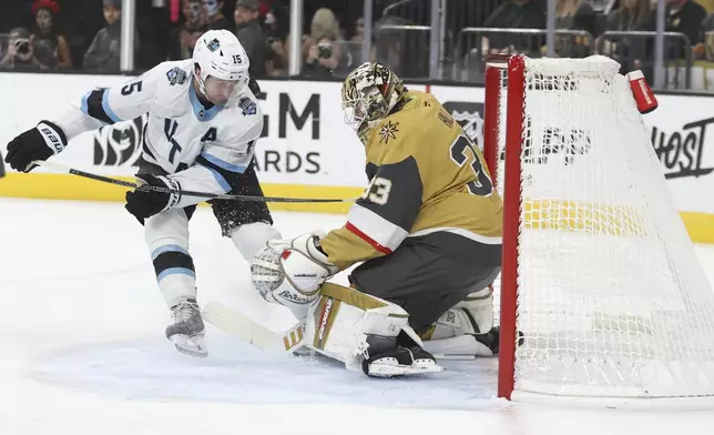 Utah Hockey Club center Alexander Kerfoot (15) collides into Vegas Golden Knights goaltender Adin Hill (33) during the first period of an NHL hockey game Saturday, Nov. 2, 2024, in Las Vegas. (AP Photo/Ian Maule)