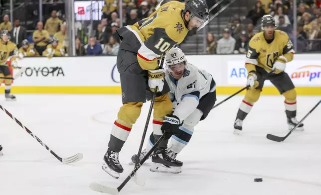 Utah Hockey Club center Barrett Hayton (27) attempts to steal the puck from Vegas Golden Knights center Nicolas Roy (10) during the second period of an NHL hockey game Saturday, Nov. 2, 2024, in Las Vegas. (AP Photo/Ian Maule)