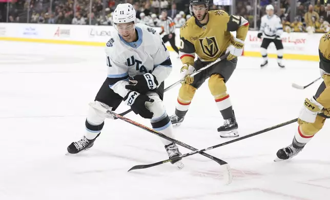 Utah Hockey Club right wing Dylan Guenther (11) loses his stick while skating past Vegas Golden Knights center Nicolas Roy (10) during the first period of an NHL hockey game Saturday, Nov. 2, 2024, in Las Vegas. (AP Photo/Ian Maule)