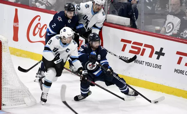 Utah Hockey Club's Clayton Keller (9) and Winnipeg Jets' Josh Morrissey (44) battle for the puck during the first period of an NHL hockey game in Winnipeg, Manitoba, Tuesday Nov. 5, 2024. (Fred Greenslade/The Canadian Press via AP)