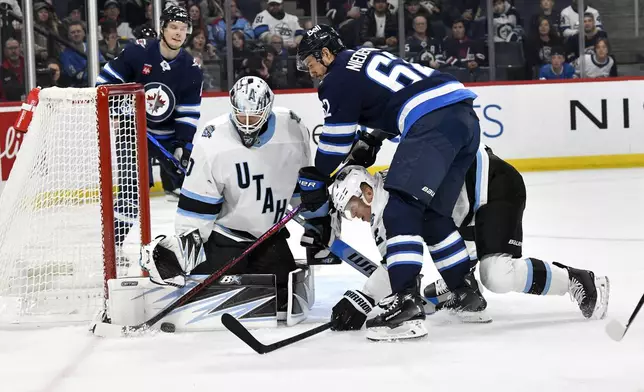 Utah Hockey Club goaltender Karel Vejmelka (70) makes a save on Winnipeg Jets' Nino Niederreiter (62) as Utah's Olli Maatta (2) defends during the second period of an NHL hockey game in Winnipeg, Manitoba, Tuesday Nov. 5, 2024. (Fred Greenslade/The Canadian Press via AP)