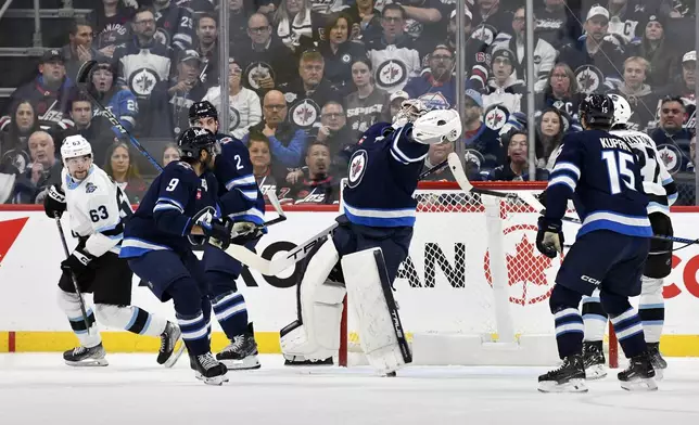 Winnipeg Jets' goaltender Connor Hellebuyck (37) reaches to grab a bouncing puck after a Utah Hockey Club shot during the second period of an NHL hockey game in Winnipeg, Manitoba, Tuesday Nov. 5, 2024. (Fred Greenslade/The Canadian Press via AP)