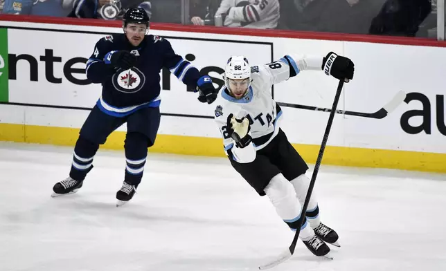 Utah Hockey Club's Nick Schmaltz (8) grabs a bouncing puck in front of Winnipeg Jets' Neal Pionk (4) during the first period of an NHL hockey game in Winnipeg, Manitoba, Tuesday Nov. 5, 2024. (Fred Greenslade/The Canadian Press via AP)